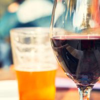 Red,Wine,And,Beer,Glass,On,Wooden,Table,With,Blurry